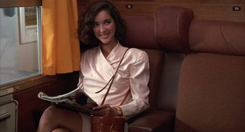 Movie still from “Dirty Rotten Scoundrels” (1988), directed by Frank Oz – A woman sitting on a train holding a magazine; Medium shot, High angle