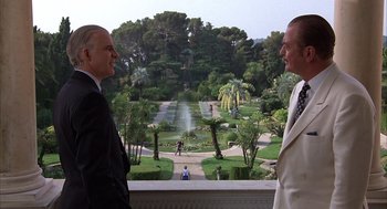 Movie still from “Dirty Rotten Scoundrels” (1988), directed by Frank Oz – Two men in suits looking out a window at a garden; Wide shot, Over the shoulder angle