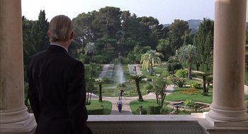 Movie still from “Dirty Rotten Scoundrels” (1988), directed by Frank Oz – An older man in a suit looking out over a garden; Extreme Wide shot, Over the shoulder angle