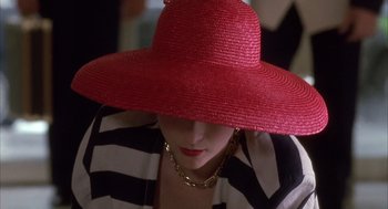 Movie still from “Dirty Rotten Scoundrels” (1988), directed by Frank Oz – A woman wearing a red hat with a gold chain around her neck; Close Up shot, Low angle