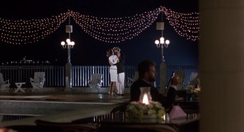 Movie still from “Dirty Rotten Scoundrels” (1988), directed by Frank Oz – Two people are kissing in front of lights at night; Wide shot, Over the shoulder angle