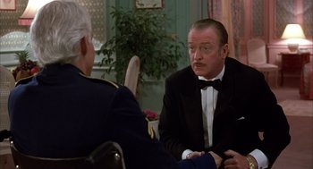 Movie still from “Dirty Rotten Scoundrels” (1988), directed by Frank Oz – A man in a tuxedo sitting next to another man in a military uniform; Medium shot, Over the shoulder angle