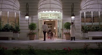 Movie still from “Dirty Rotten Scoundrels” (1988), directed by Frank Oz – A couple of men standing in front of a building; Wide shot, Low angle