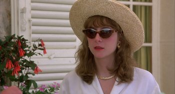 Movie still from “Dirty Rotten Scoundrels” (1988), directed by Frank Oz – A woman wearing sunglasses and a straw hat; Close Up shot, Over the shoulder angle