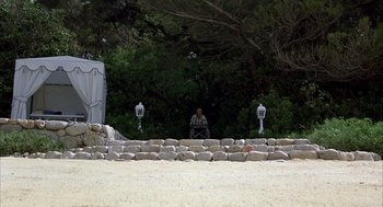 A man sitting on top of a stone wall near trees