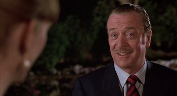 Movie still from “Dirty Rotten Scoundrels” (1988), directed by Frank Oz – A person wearing a suit and tie; Close Up shot, Over the shoulder angle