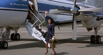 Movie still from “Dirty Rotten Scoundrels” (1988), directed by Frank Oz – A woman in a business suit waves to the camera; Wide shot, High angle