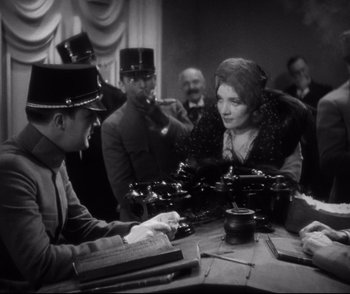 Movie still from “Dishonored” (1931), directed by Josef von Sternberg – A group of men and women sitting around a wooden table; Medium shot, High angle