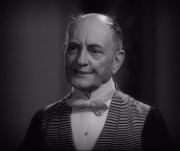 Movie still from “Dishonored” (1931), directed by Josef von Sternberg – An older man wearing a striped vest and bow tie; Close Up shot, Low angle