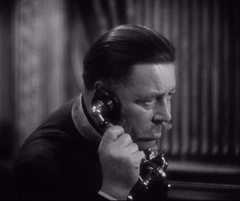 Movie still from “Dishonored” (1931), directed by Josef von Sternberg – A man talking on a phone while wearing a suit and tie; Close Up shot, High angle