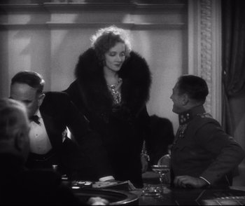 Movie still from “Dishonored” (1931), directed by Josef von Sternberg – An old photo of a man and a woman at a table; Medium shot, Over the shoulder angle