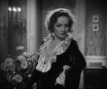 Movie still from “Dishonored” (1931), directed by Josef von Sternberg – A black and white photo of a woman with a bouquet of flowers; Medium shot, High angle