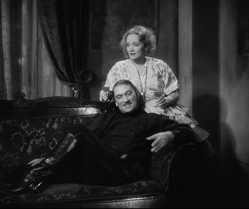 Movie still from “Dishonored” (1931), directed by Josef von Sternberg – An older man sitting on a couch next to a younger woman; Medium shot, Low angle