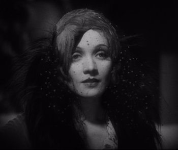Movie still from “Dishonored” (1931), directed by Josef von Sternberg – A black and white photo of a woman wearing a feather headdress; Close Up shot, Low angle