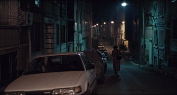 Movie still from “Distant” (2002), directed by Nuri Bilge Ceylan – A woman walking down a street at night; Extreme Wide shot, High angle