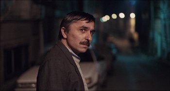 Movie still from “Distant” (2002), directed by Nuri Bilge Ceylan – A man with a mustache standing in the dark; Close Up shot, Low angle