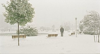 Movie still from “Distant” (2002), directed by Nuri Bilge Ceylan – A person standing in the snow near a bench; Extreme Wide shot, High angle