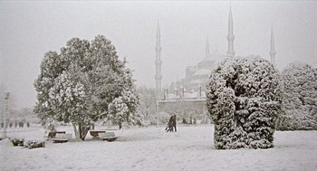 Movie still from “Distant” (2002), directed by Nuri Bilge Ceylan – Two people are playing in the snow in front of a mosque; Extreme Wide shot, Low angle
