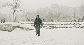 Movie still from “Distant” (2002), directed by Nuri Bilge Ceylan – A man walking in the snow in a park; Wide shot, Low angle