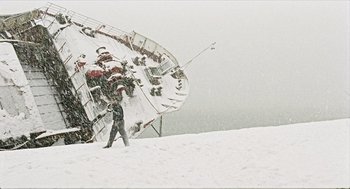 Movie still from “Distant” (2002), directed by Nuri Bilge Ceylan – A person walking on a snow covered slope near a boat; Extreme Wide shot, Low angle