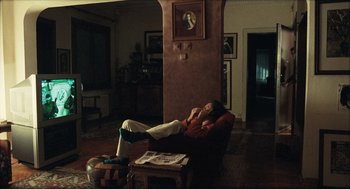 Movie still from “Distant” (2002), directed by Nuri Bilge Ceylan – A person sitting in a chair in a living room; Wide shot, High angle