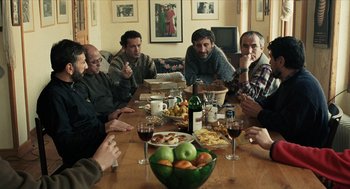 Movie still from “Distant” (2002), directed by Nuri Bilge Ceylan – A group of people sitting around a table with a bowl of fruit on it; Wide shot, High angle