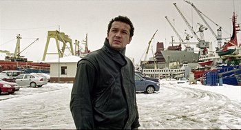 Movie still from “Distant” (2002), directed by Nuri Bilge Ceylan – A man standing in front of a construction site; Medium shot, Low angle