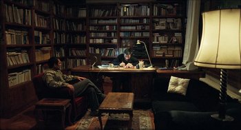 Movie still from “Distant” (2002), directed by Nuri Bilge Ceylan – Two people sitting at a desk in a library; Wide shot, High angle
