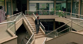Movie still from “Distant” (2002), directed by Nuri Bilge Ceylan – A man walking down a set of stairs in an office building; Wide shot, High angle