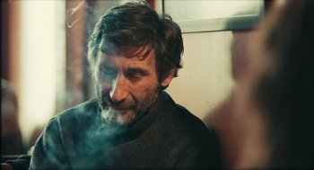 Movie still from “Distant” (2002), directed by Nuri Bilge Ceylan – A man with a beard is smoking a cigarette; Close Up shot, Over the shoulder angle