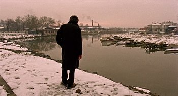 Movie still from “Distant” (2002), directed by Nuri Bilge Ceylan – A man standing on the shore of a body of water; Wide shot, Low angle