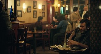 Movie still from “Distant” (2002), directed by Nuri Bilge Ceylan – A group of people sitting at a table in a restaurant; Medium shot, Over the shoulder angle