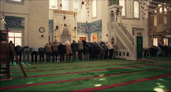 Movie still from “Distant” (2002), directed by Nuri Bilge Ceylan – A group of people standing in front of a wall in a mosque; Extreme Wide shot, High angle