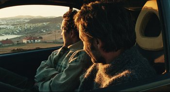Movie still from “Distant” (2002), directed by Nuri Bilge Ceylan – Two men sitting in the back seat of a car looking out the window; Medium shot, Over the shoulder angle