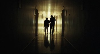 Movie still from “Distant” (2002), directed by Nuri Bilge Ceylan – Two people are walking down a hallway in a building; Wide shot, Low angle