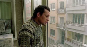 Movie still from “Distant” (2002), directed by Nuri Bilge Ceylan – A man standing in front of a window looking outside; Medium shot, Low angle