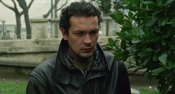 Movie still from “Distant” (2002), directed by Nuri Bilge Ceylan – A person wearing a jacket near a tree; Close Up shot, Low angle