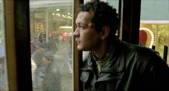 Movie still from “Distant” (2002), directed by Nuri Bilge Ceylan – A man looking out of a window at a crowded street; Close Up shot, Low angle