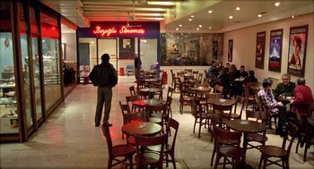 Movie still from “Distant” (2002), directed by Nuri Bilge Ceylan – People are sitting at tables in an empty restaurant; Extreme Wide shot, High angle