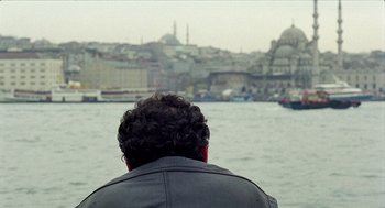 Movie still from “Distant” (2002), directed by Nuri Bilge Ceylan – A man looking out over a body of water; Close Up shot, Over the shoulder angle