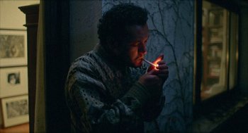 Movie still from “Distant” (2002), directed by Nuri Bilge Ceylan – A man is lighting a cigarette in the dark; Medium shot, Low angle