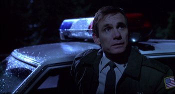 Movie still from “Disturbing Behavior” (1998), directed by David Nutter – A man sitting in the back of a police car at night; Close Up shot, Low angle