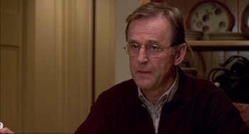 Movie still from “Disturbing Behavior” (1998), directed by David Nutter – An older man wearing glasses is sitting down; Close Up shot, Over the shoulder angle