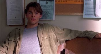 Movie still from “Disturbing Behavior” (1998), directed by David Nutter – A man sitting in front of a sign; Close Up shot, High angle