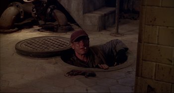 Movie still from “Disturbing Behavior” (1998), directed by David Nutter – A man is laying in a hole in the ground; Wide shot, High angle