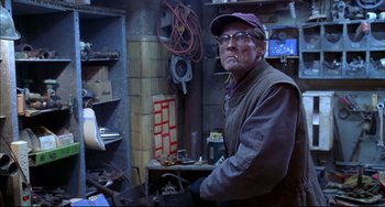 Movie still from “Disturbing Behavior” (1998), directed by David Nutter – A man standing in front of a table with tools on top of it; Medium shot, Low angle