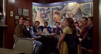 Movie still from “Disturbing Behavior” (1998), directed by David Nutter – A group of people sitting at a table in front of a mural; Wide shot, High angle