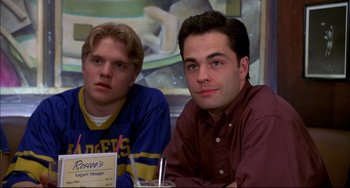 Movie still from “Disturbing Behavior” (1998), directed by David Nutter – Two young men sitting at a table in front of a painting; Close Up shot, High angle