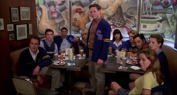 Movie still from “Disturbing Behavior” (1998), directed by David Nutter – A man standing in front of a group of people sitting at a table; Medium shot, Low angle