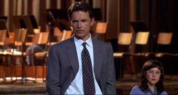 Movie still from “Disturbing Behavior” (1998), directed by David Nutter – A man in a suit and tie standing in front of a microphone; Close Up shot, High angle